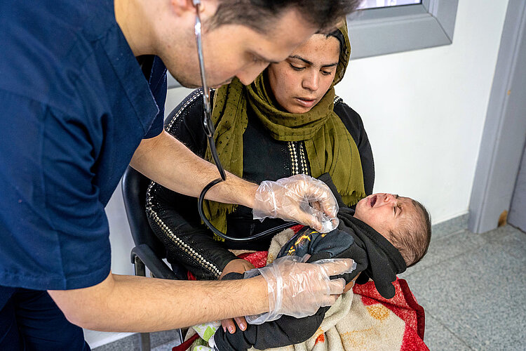 Arzt hört Baby ab in Armen der Mutter 