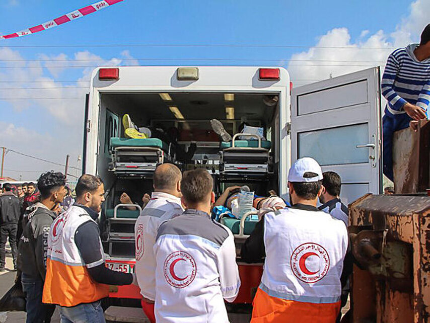 Foto: Helfer vor einem Rettungswagen mit vier liegenden Verletzen auf Tragen