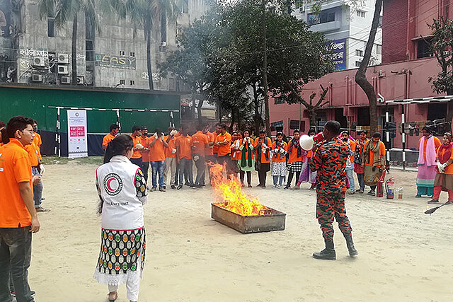 bangladeschische Männer und Frauen um ein Feuer bei Übung 