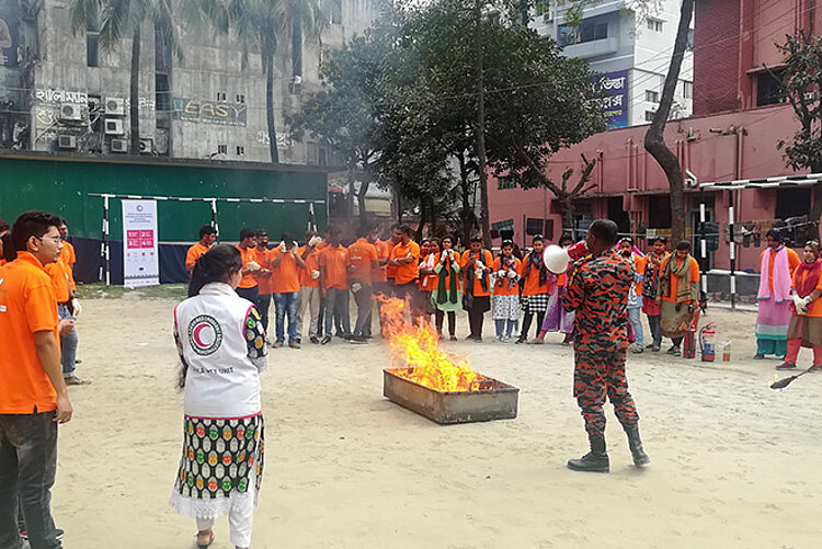 bangladeschische Männer und Frauen um ein Feuer bei Übung 