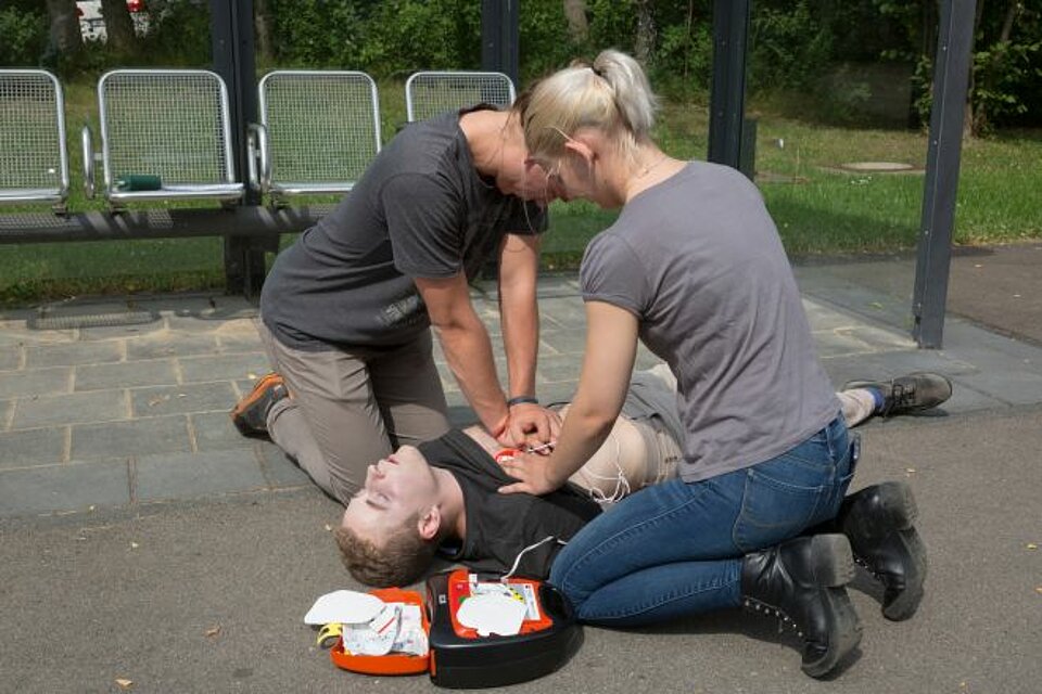 Ein Mann und eine Frau wenden die Herz-Lungen-Wiederbelebung mit Defibrillator an.