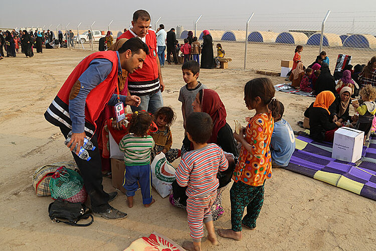 Ein Mitarbeiter des Irakischen Roten Halbmonds mit Kindern.