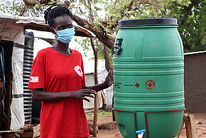 Rotkreuzlerin in Uganda neben einer Handwascheinrichtung