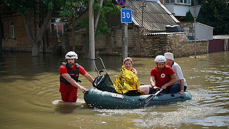 HElfer des Ukrainischen Roten Kreuzes bringen Menschen mit einem Boot in Sicherheit.