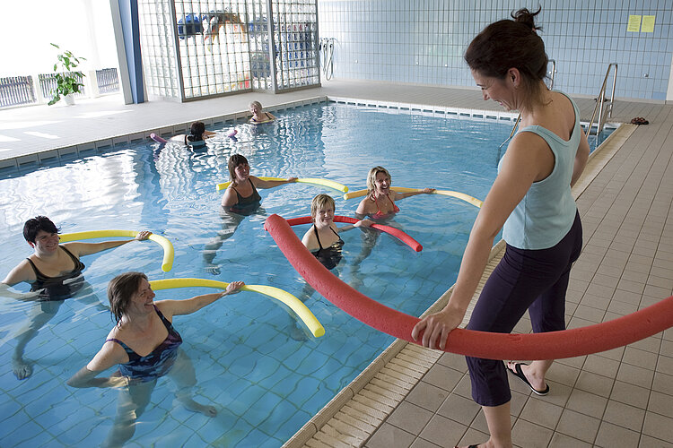 Frauen mit Schwimmnudeln im Schwimmbecken
