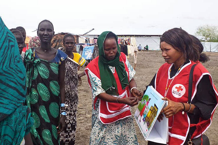 Rotkreuz-Freiwillige im Gespräch mit sudanesischen Geflüchteten