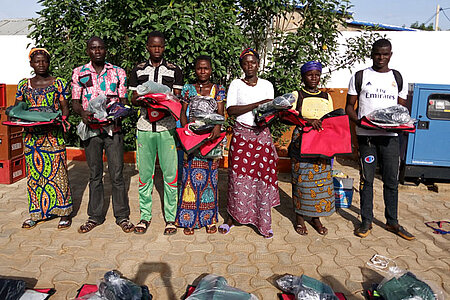 Foto: 7 Frauen und Männer aus Togo mit Rotkreuz-Ausrüstung in der Hand stehen in einer Reihe