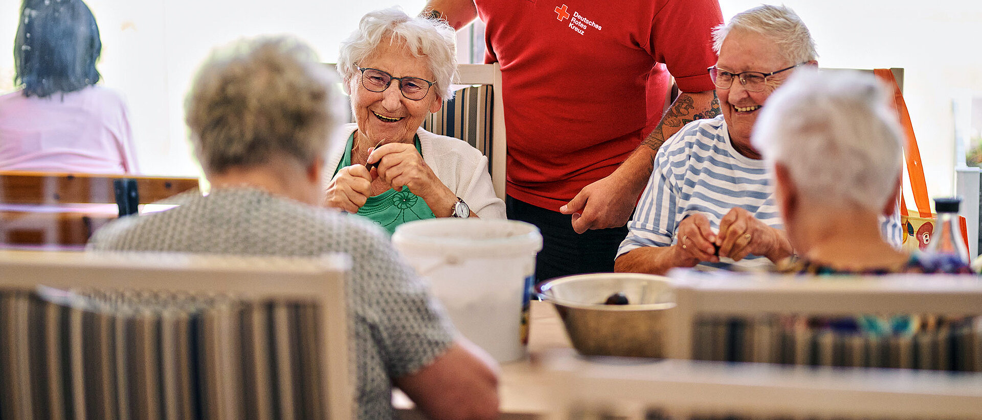 Lachende Seniorengruppe mit DRK-Pfleger