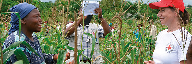 Eine togolesische Frau mit einer DRK-Mitarbeiterin in einem Maisfeld