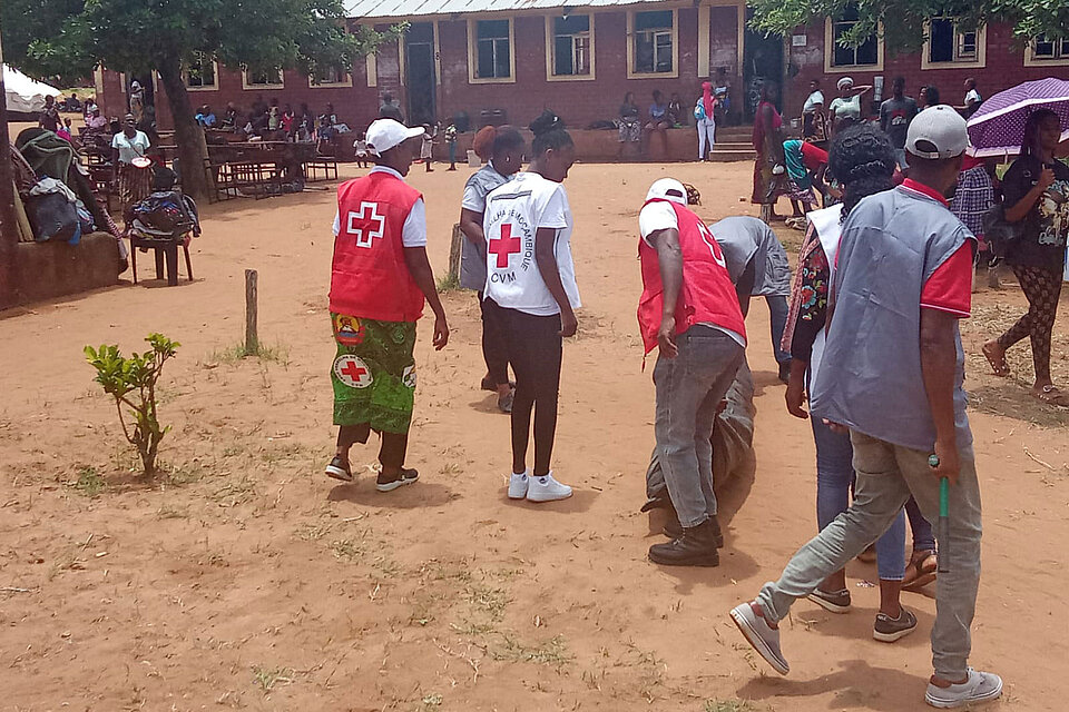 Helfende mit zusammengerolltem Zelt