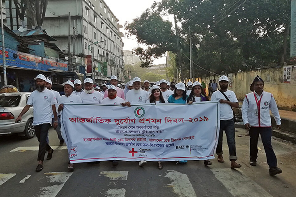 Foto: Menschen aus mit Banner zur Sensibilisierung für Katastrophen in Asien