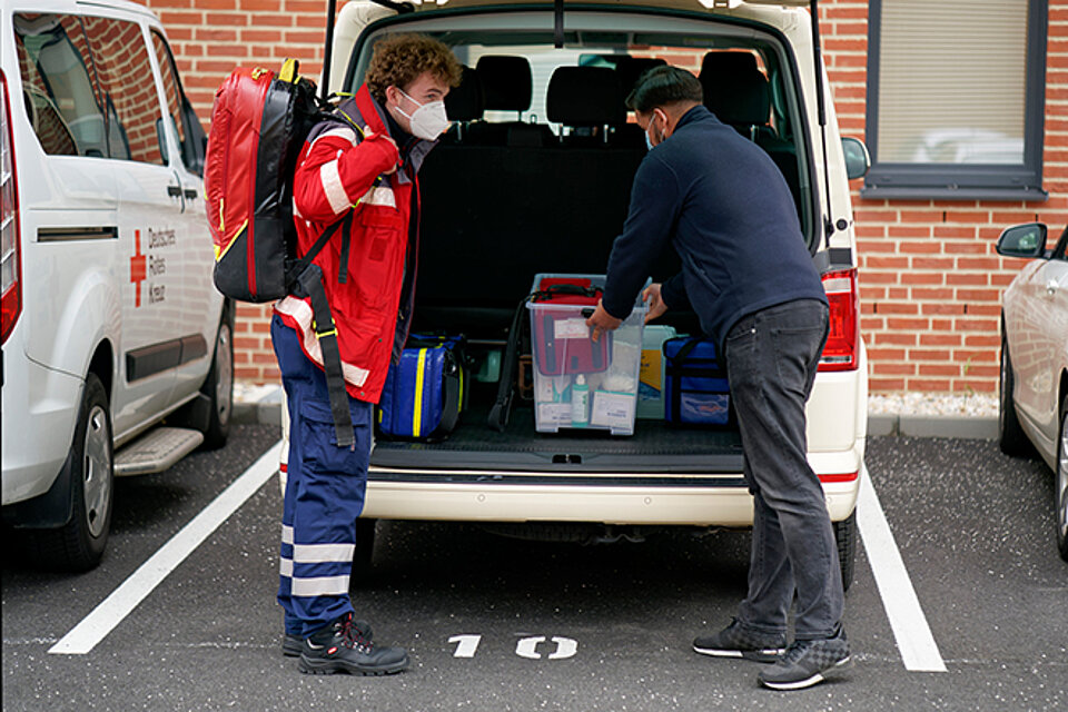 DRKler vor Kofferraum eines Einsatzwagens