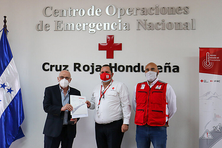 Drei Männer (zwei von ihnen Rotkreuzler) mit einem Vertrag Wissenschaftliche Zusammenarbeit für Hilfe in Honduras und Guatemala