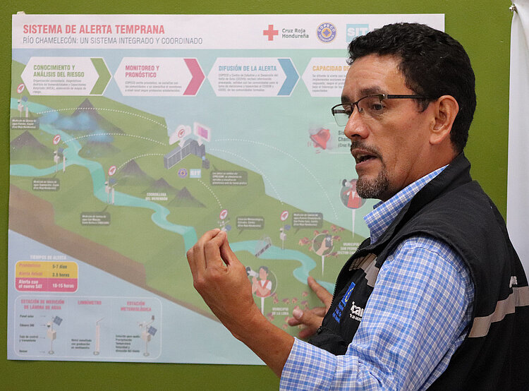 Ein Mitarbeiter des Honduranischen Roten Kreuzes steht vor einer Landkarte 