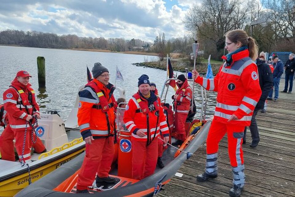 Sarah Wöltje von der Lübecker DRK-Bereitschaft gibt die symbolische Fackel im Segler-Hafen in Schlutup an ihre Kameraden von der Wasserwacht weiter.