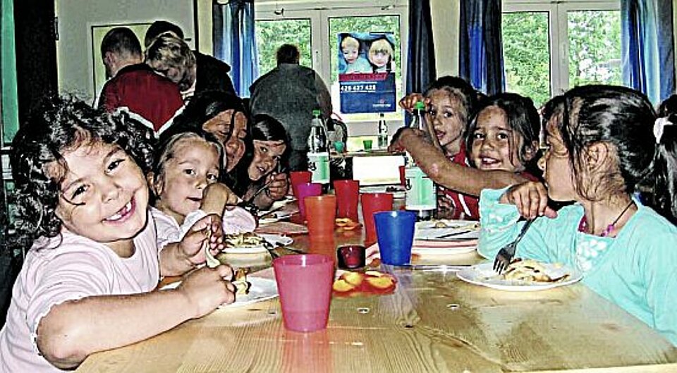 Foto: lachende Kinder mit Migrationshintergrund an einem Esstisch