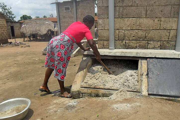 Togolesin durchmischt Kompostdünger am Fuß einer Latrine