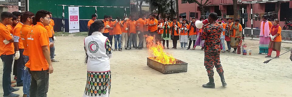 bangladeschische Männer und Frauen um Feuer bei Übung zu Naturkatastrophen