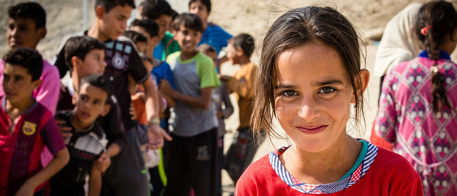 lächelndes Mädchen im Irak vor Kindergruppe