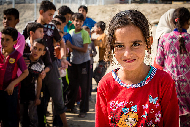 lächelndes Mädchen im Irak vor Kindergruppe