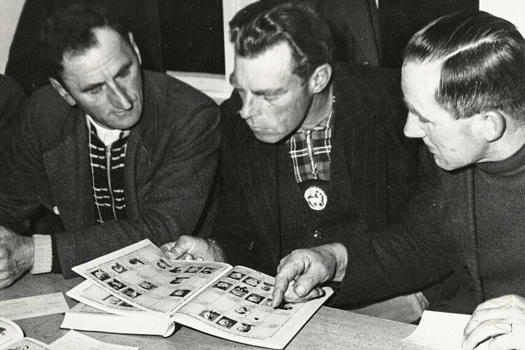 Im Lager Friedland sehen sich Heimkehrer die Bildlisten mit den Porträts vermisster Personen an, 1955 (DRK)