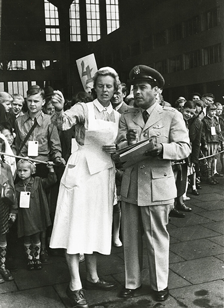 Eine Gruppe Kinder mit einer Betreuerin vom DRK und einem Offizier der US-Luftwaffe auf dem Flughafen Berlin-Tempelhof vor dem Abflug (Paul Wittig/ DRK)