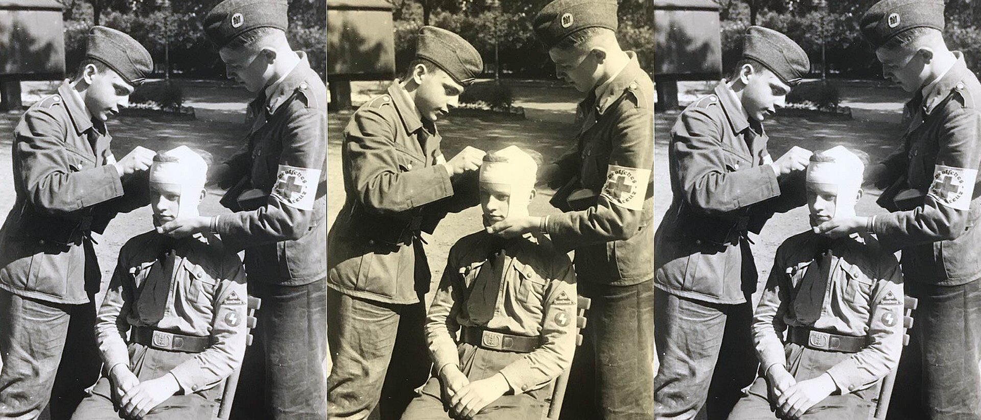 Zwei uniformierte Jungen verbinden Kopf eines dritten Jungen