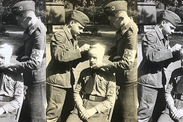 Zwei uniformierte Jungen verbinden Kopf eines dritten Jungen