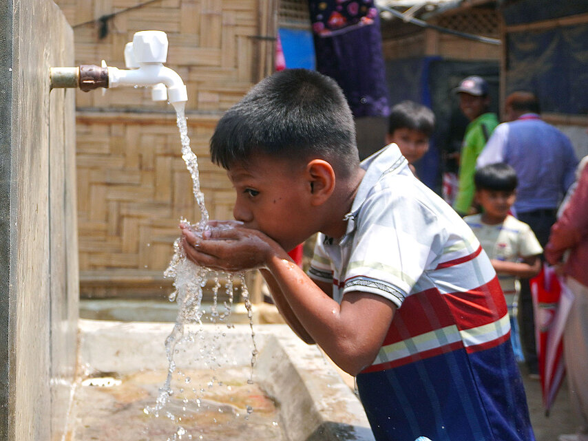 Junge trinkt an Wasserstelle