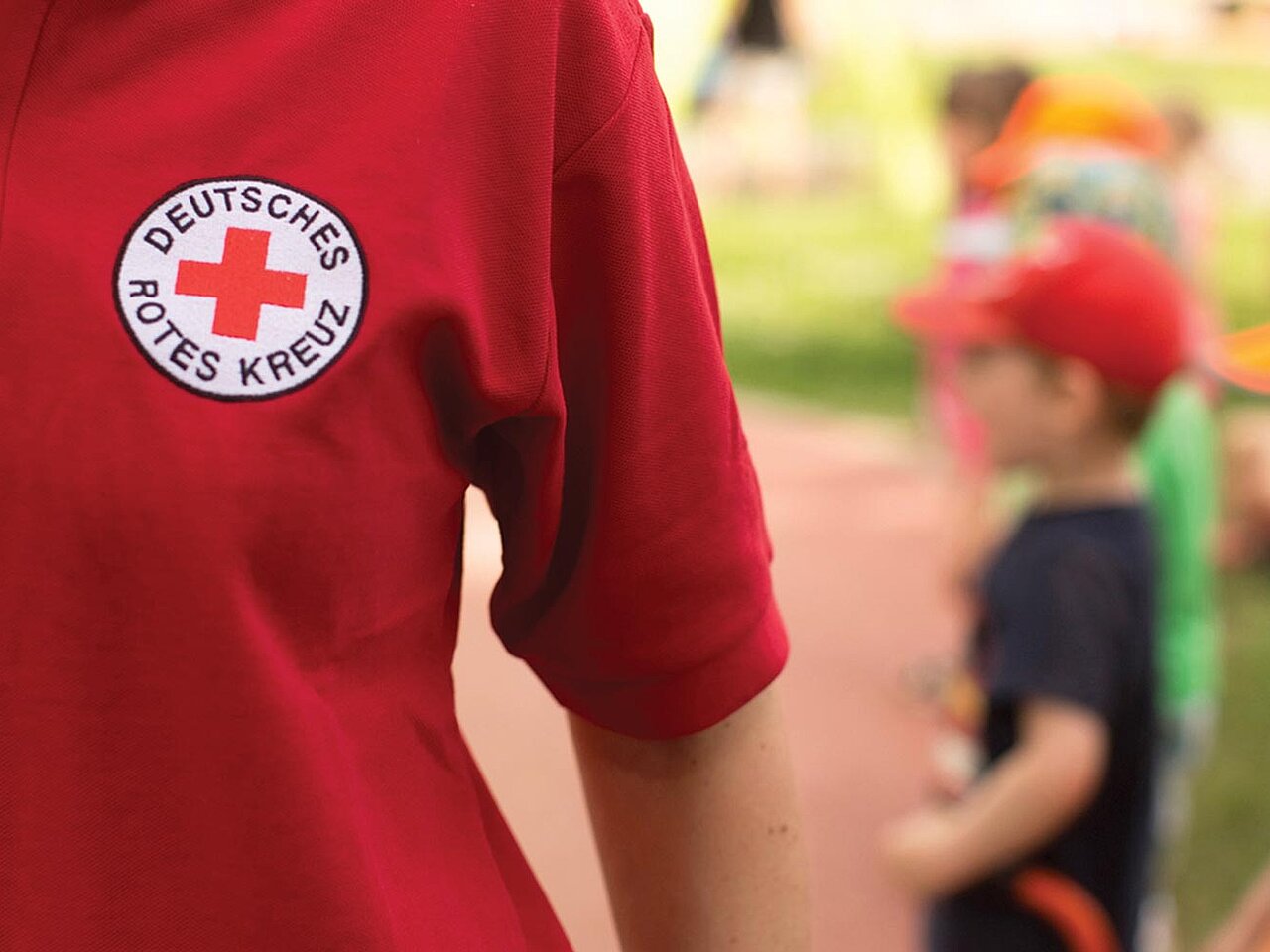 Frau mit DRK-Shirt Kinder unscharf im Hintergrund