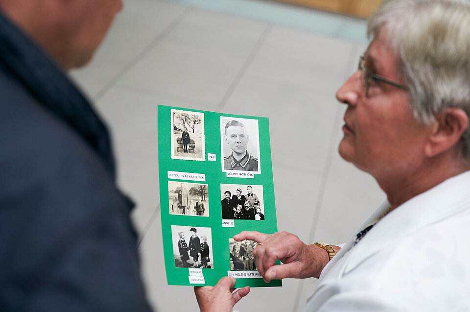 Person, die Anfrage nach im 2. Weltkrieg vermissten Familienangehörigen stellte, zeigt Kameramann alte Fotos.