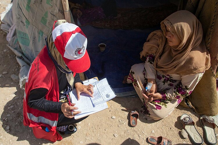 Helferin des Afghanischen Roten Halbmondes spricht mit einer Frau 
