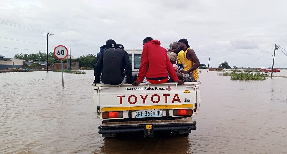 Ein Auto, finanziert vom DRK, fährt durch überflutete Gebiete in Mosambik. Auf der Ladefläche sitzen Menschen.