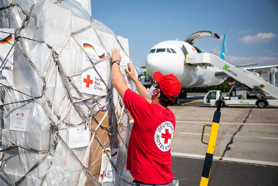 Ein DRK-Mitarbeiter steht auf dem Rollfeld des Flughafens Berlin Schönefeld und inspiziert eine Landung mit Hilfsgütern.