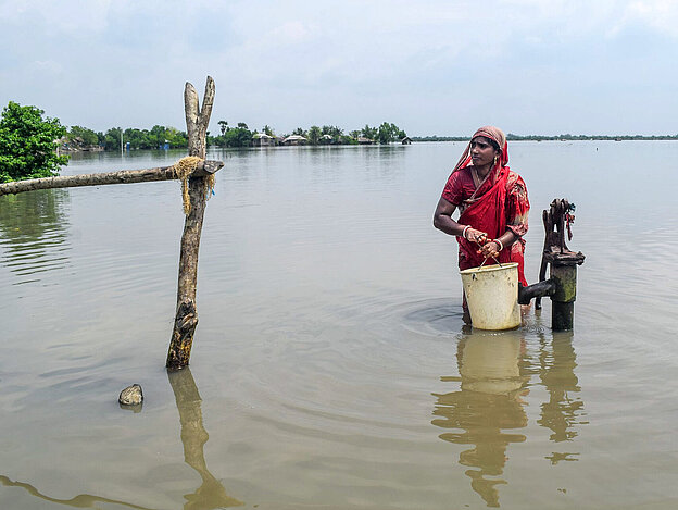 Frau an Wasserpumpe in Gewässer