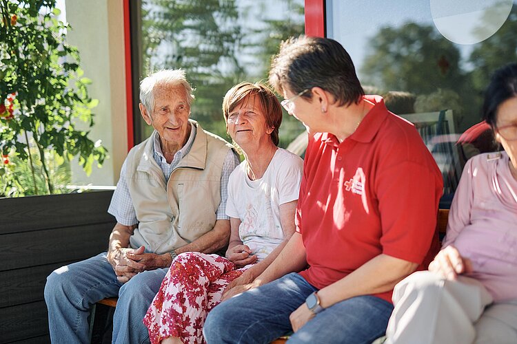 Senioren und Pflegerin sitzen in Sonne