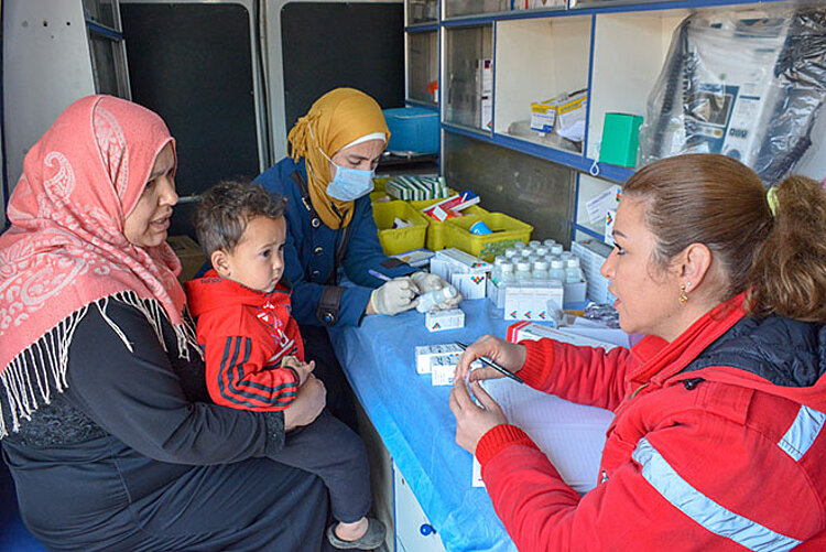 Foto: syrische Ärztin im Gespräch mit einer Mutter und ihrem Kind