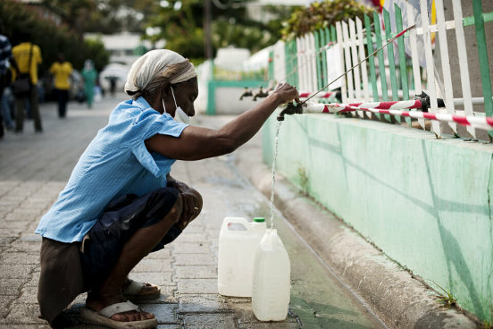 Foto: Eine Frau zapft Wasser aus einem Hahn.