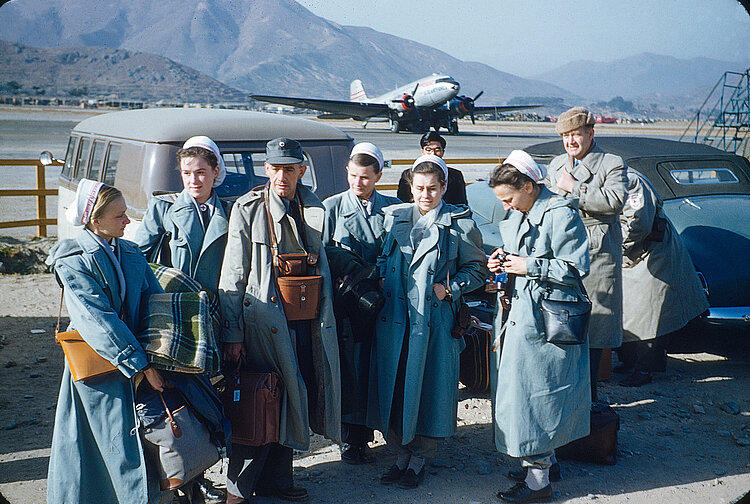 Eine Gruppe von Ärzten und Schwestern steht vor einem Flugzeug 