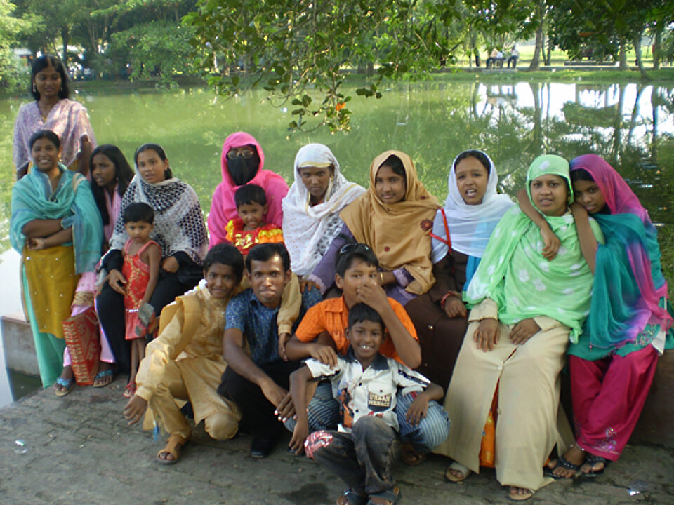 Foto: Ein Familie in Bangladesch an einem Teich, alle sind bunt und festlich angezogen