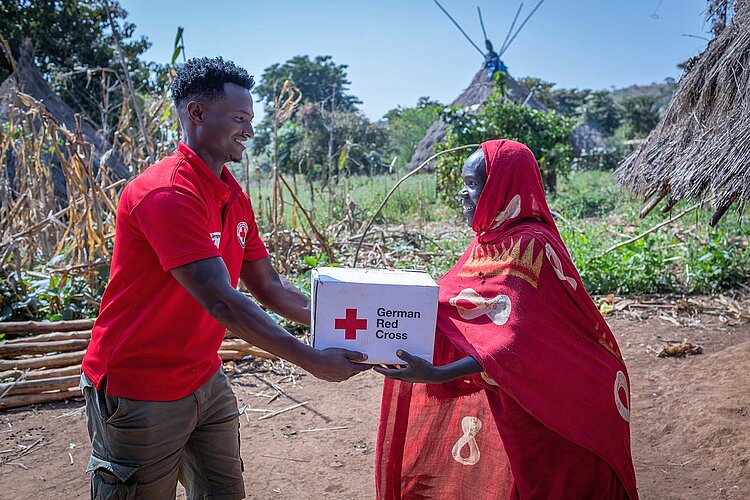 Freiwilliger übergibt DRK-Karton an Frau