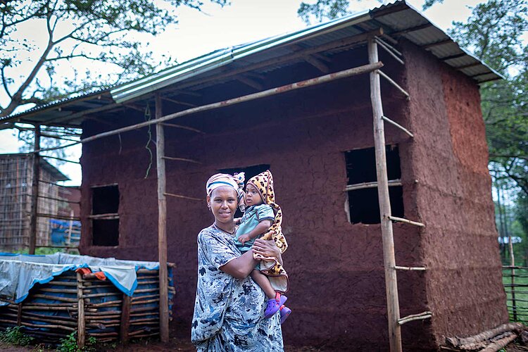 Mutter und Baby vor neuer Hütte