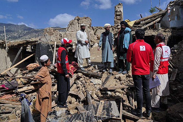 Männer stehen mit Helfern auf Erbbebentrümmern in Afghanistan