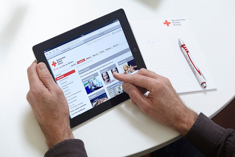 Mensch an einem Laptop. Angezeigt wird die DRK-Homepage