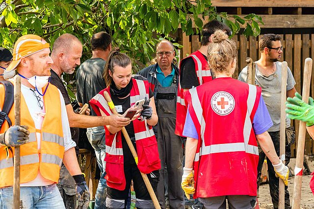 DRKlerinnen und weitere Helfende mit Spaten