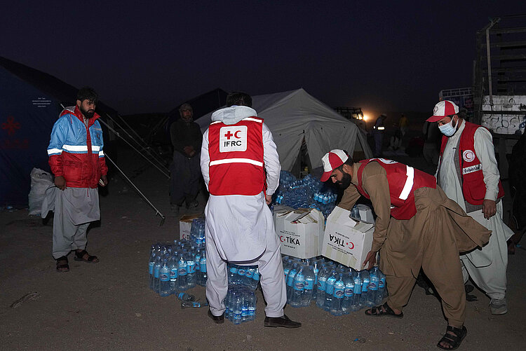 Helfer des Afghanischen Roten Halbmondes mit Wasserflaschen im Erdbebengebiet