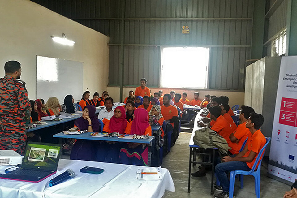bangladeschische Männer und Frauen an Tischen in Schulungsraum