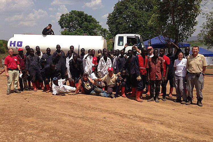 Foto: Große Gruppe Rotkreuz-Mitarbeiter vor einem Wassetruck