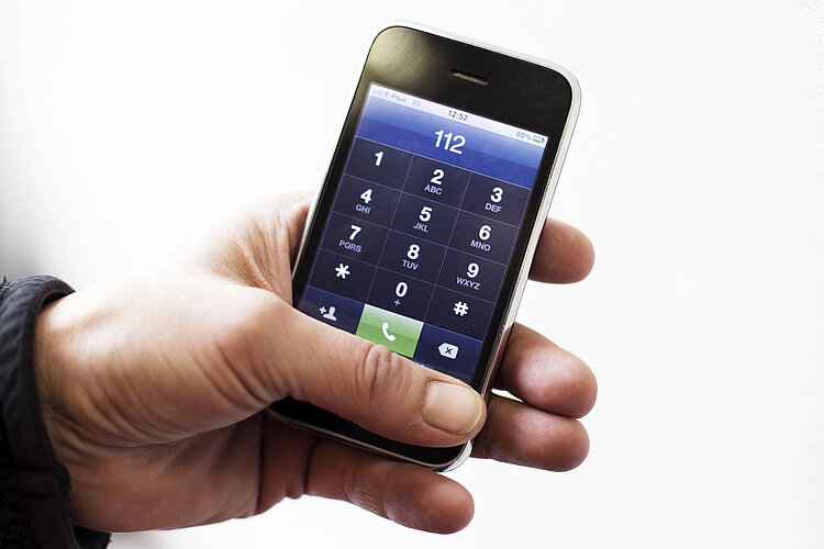 Hand hält Telefon mit Notrufnummer