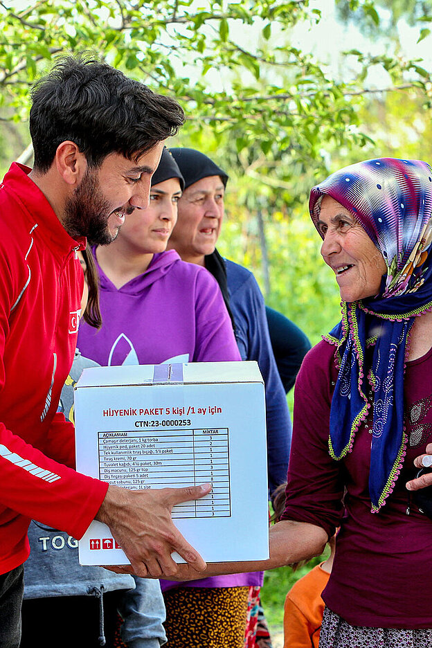 Volunteer giving relief items to woman with child
